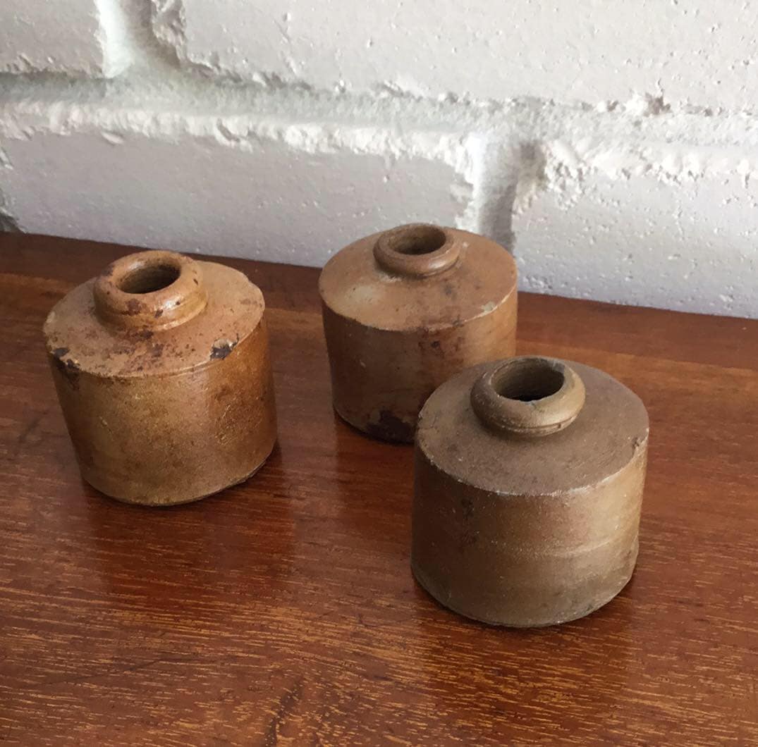 Top view of three stoneware penny inkwells showing their collared necks and worn glaze